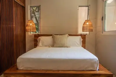 a bedroom with a bed with white sheets and two lamps at Arroyo Tranquilo - Steps to the Beach in Santa Teresa Beach
