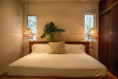 a bedroom with a bed with two lamps and a plant at Arroyo Tranquilo - Steps to the Beach in Santa Teresa Beach