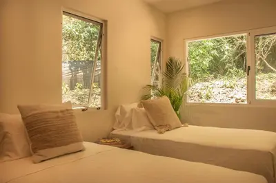 a bedroom with two beds and two windows at Arroyo Tranquilo - Steps to the Beach in Santa Teresa Beach