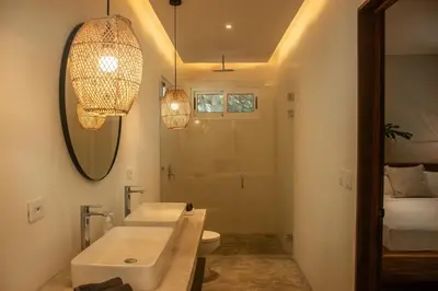 a bathroom with two sinks and a toilet and a mirror at Arroyo Tranquilo - Steps to the Beach in Santa Teresa Beach