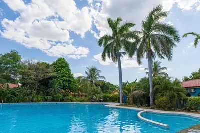 a swimming pool with palm trees in a resort at Casa Colibrí - Villagio 372A in Potrero
