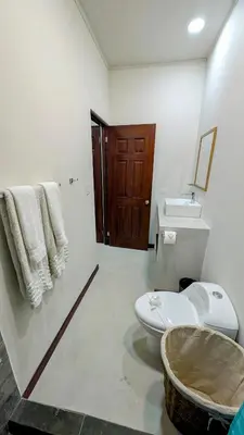 a white bathroom with a toilet and a sink at Los Mangos Nosara in Nosara