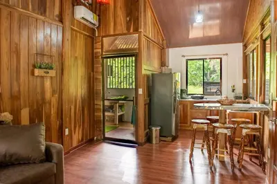 a kitchen with a refrigerator and a table and chairs at ROQUI Cozy Beachfront Cabin in Uvita