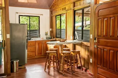 a kitchen with wooden cabinets and a counter with stools at ROQUI Cozy Beachfront Cabin in Uvita