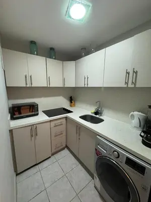 a kitchen with white cabinets and a washing machine at Casa Arte Jaco in Jacó