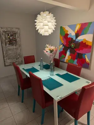 a dining room table with red chairs and a painting at Casa Arte Jaco in Jacó