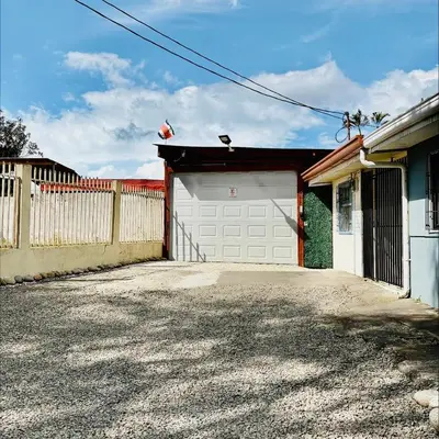 a garage with a white door and a fence at Brisa Amatista - Casa completa y centrica en San Ramón #2 in San Ramón
