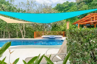 a swimming pool with a blue umbrella over it at Altavista #3 in Jacó