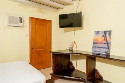 a room with a desk with a tv on a wall at Altavista #3 in Jacó