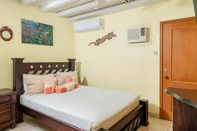 a bedroom with a bed with white sheets and pink pillows at Altavista #3 in Jacó