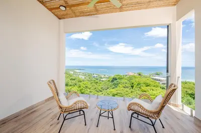 a balcony with two chairs and a glass table at Luxury Oceanview Penthouse, Breathtaking Sunsets in Tamarindo