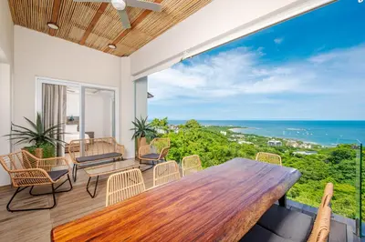 a patio with a wooden table and chairs and the ocean at Luxury Oceanview Penthouse, Breathtaking Sunsets in Tamarindo