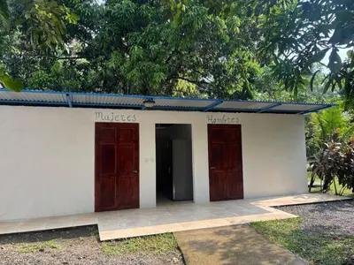 a small white building with two wooden doors at Camping Finca Planeta Sano in Naranjito