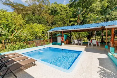 a swimming pool with chairs and a house at Camping Finca Planeta Sano in Naranjito
