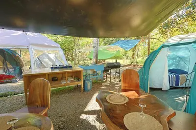 a group of tents with a wooden table and chairs at Camping Finca Planeta Sano in Naranjito