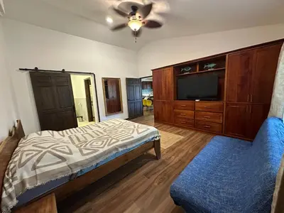 a bedroom with a bed and a tv and a couch at La Chozita in Tamarindo