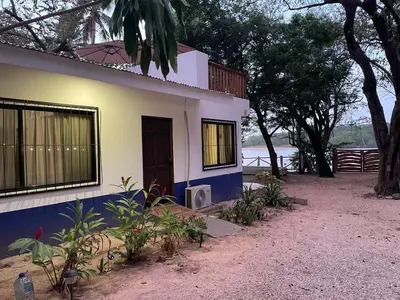 a house with blue and white walls and trees at La Chozita in Tamarindo