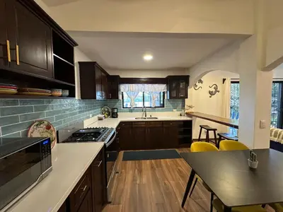 a kitchen with wooden cabinets and a table in it at La Chozita in Tamarindo