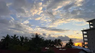 a cloudy sky at sunset with palm trees and buildings at La Flor beach Condos in Jacó
