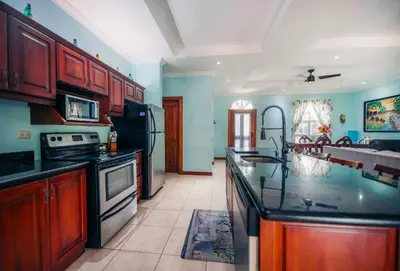 a kitchen with wooden cabinets and a black counter top at Villa Atardecer by Vacation Pura Vida in Bejuco