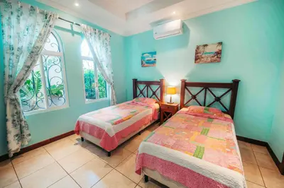 a bedroom with two beds and a window at Villa Atardecer by Vacation Pura Vida in Bejuco