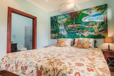 a bedroom with a bed with a painting on the wall at Villa Atardecer by Vacation Pura Vida in Bejuco