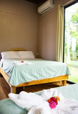 two beds in a room with towels and a window at Chiri's Cabin in San Gerardo