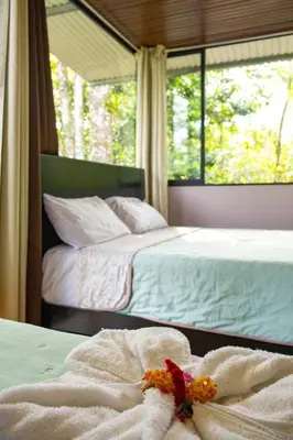 a bedroom with two beds with towels and a window at Chiri's Cabin in San Gerardo