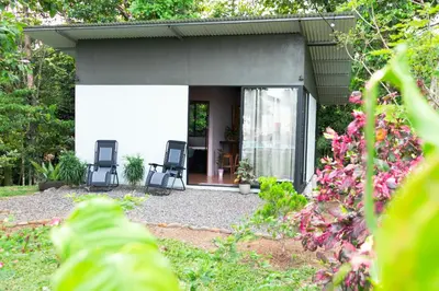 a house with two chairs in a garden at Chiri's Cabin in San Gerardo