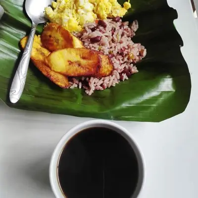 a plate of food with rice and meat on a banana leaf at Somos Zapatón Catarata EL REY in Zapatón