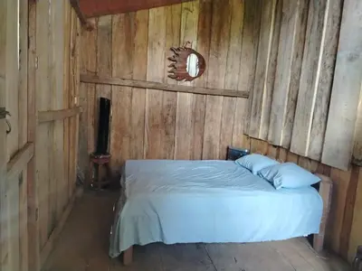 a bedroom with a bed in a wooden wall at Somos Zapatón Catarata EL REY in Zapatón