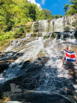 a woman holding a flag in front of a waterfall at Somos Zapatón Catarata EL REY in Zapatón
