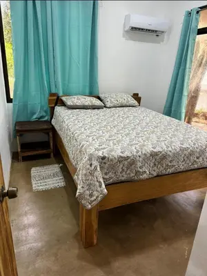 a bed in a bedroom with a blue curtain at New casita walking distance to Avellanas beach in Río Sequito