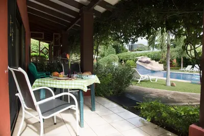 a table and chairs on a patio with a pool at Apartments-Villas Playa Potrero 1 in Potrero