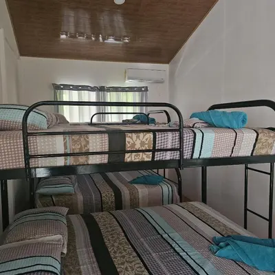 three bunk beds in a room with a window at Cabaña y Piscina el Lorito in Uvita