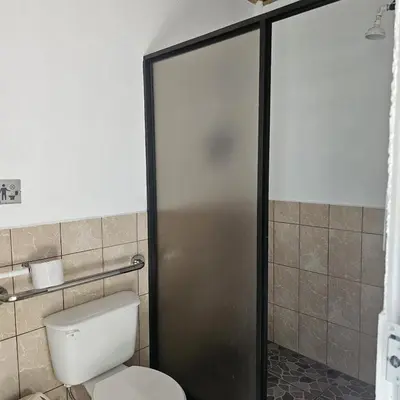 a bathroom with a toilet and a glass shower door at Cabaña y Piscina el Lorito in Uvita