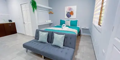 a bedroom with a blue bed and a couch at Forest apartments studio F3, walking to the beach! in Jacó
