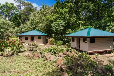 two small buildings with blue roofs in a garden at Awake Uvita in Uvita