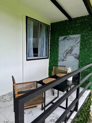 a patio with two chairs and a table and a green wall at Mini Casa Aura in Fortuna