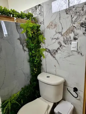 a bathroom with a white toilet and plants on the wall at Mini Casa Aura in Fortuna