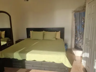 a bedroom with a bed with a green comforter and a mirror at Beach Front Condo for 10 people in Tamarindo