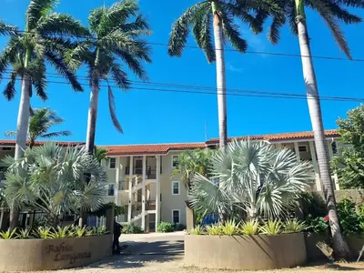 a building with palm trees in front of it at Beach Front Condo for 10 people in Tamarindo
