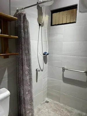 a shower with a shower curtain in a bathroom at Apartamentos Mansión Tropical in Quepos
