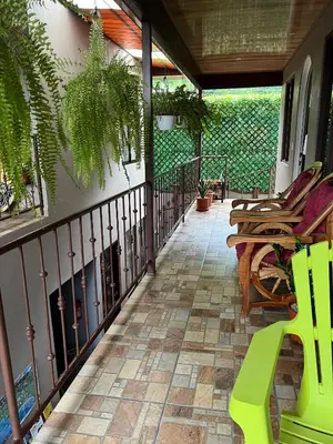 a porch with a green bench and chairs on it at Apartamentos Mansión Tropical in Quepos
