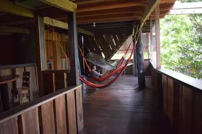 a man sitting in a hammock in a cabin at Mirador Prendas in Sarapiquí