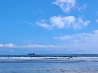 a beach with waves and an island in the ocean at Casa Lilly in Pejibaye