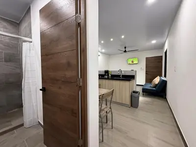 a room with a door and a kitchen with a table at Punta Leona, beach 5mn,gated parking, AC, TV, WiFi in Quebrada Ganado