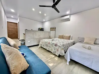 a living room with two beds and a blue couch at Punta Leona, beach 5mn,gated parking, AC, TV, WiFi in Quebrada Ganado