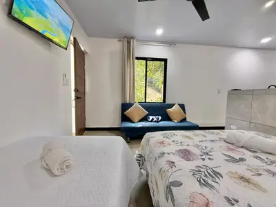 a bedroom with a bed and a blue couch at Punta Leona, beach 5mn,gated parking, AC, TV, WiFi in Quebrada Ganado