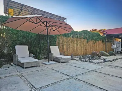 two chairs and an umbrella on a patio at Luxury Villa with rooftop infinity pool and walk away from the beach in Jacó